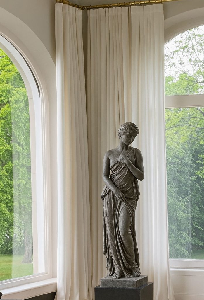 Rideaux blancs sur mesure installés avec tringle dorée, création Rho Deco à Genève, apportant élégance et lumière à un intérieur classique.