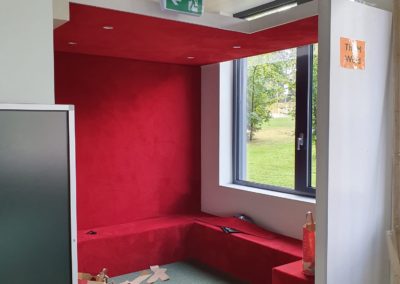 Moquette murale rouge pour espace lecture d’école – Réalisation Rho Deco