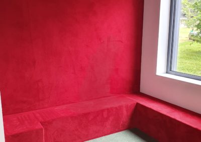 Espace lecture d’école habillé de moquette rouge pour un environnement chaleureux, sécurisé et acoustiquement confortable.