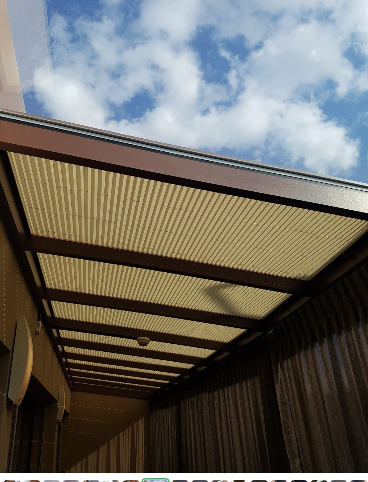 Store plissé de toit anti-UV installé à la Clinique Maison Neuve, offrant protection solaire et filtration de lumière.