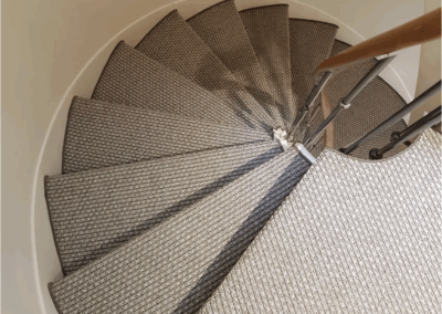 Escalier moderne recouvert de sisal naturel, avec tiges de maintien discrètes et finition minimaliste.