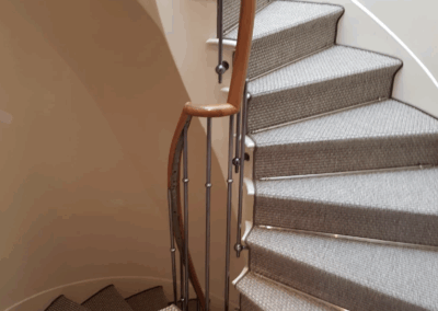 Escalier habillé de sisal naturel en pose artisanale avec tiges décoratives de maintien.