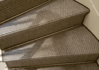 Escalier décoré en sisal tissé, maintenu par des tiges métalliques pour un rendu chaleureux et naturel.