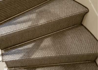 Escalier habillé en sisal naturel avec tiges de maintien métalliques et finitions sur mesure.